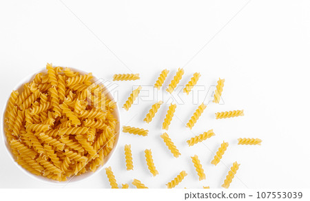 Pasta products in the form of a spiral on a plate, texture, on a white background Pasta products in the form of a spiral on a plate, texture, on a white background 107553039