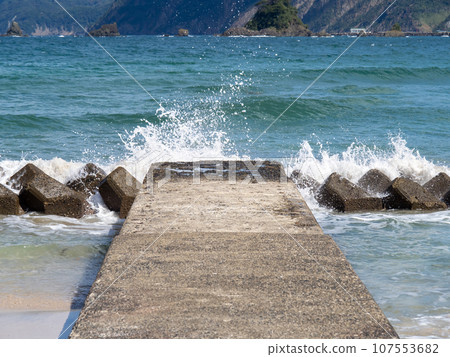 Waves crash against the wave-dissipating blocks on the coast, creating wave spray. Waves crash against the wave-dissipating blocks on the coast, creating wave spray. 107553682