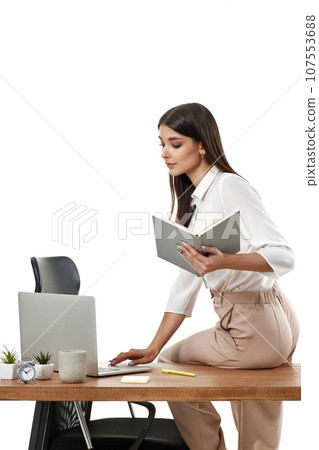 business woman holding notebook and sitting on table 107553688