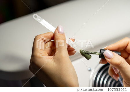 A manicurist applies gel nail polish to empty tips as a sample for future clients. Large range of gel polishes. Spa body care concept. Nail technician 107553951