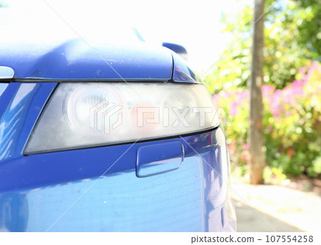 Muddy headlight on the front of the car requiring polishing 107554258