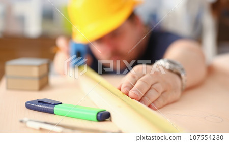 Arms of worker measuring wooden bar 107554280