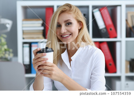 Smiling business woman drinking coffee from Smiling business woman drinking coffee from 107554359