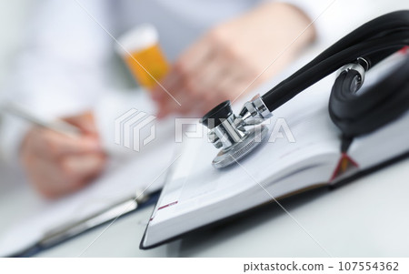Stethoscope head lying on medical forms 107554362