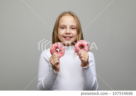 Young girl with donut having fun against gray studio wall banner background. Positive emotion. Young girl with donut having fun against gray studio wall banner background. Positive emotion. 107554686