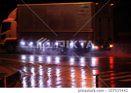 Medium-sized truck driving away on a rainy night Medium-sized truck driving away on a rainy night 107555442