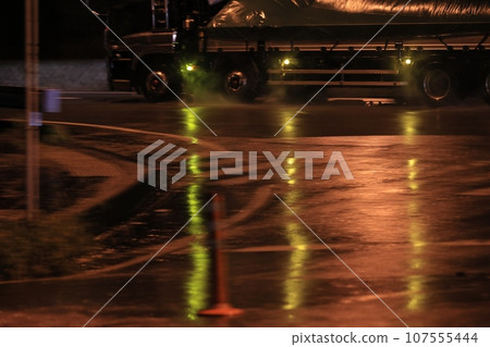 A large truck driving away on a rainy night A large truck driving away on a rainy night 107555444