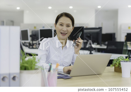 Portrait of a senior woman working at a desk in the office Portrait of a senior woman working at a desk in the office 107555452