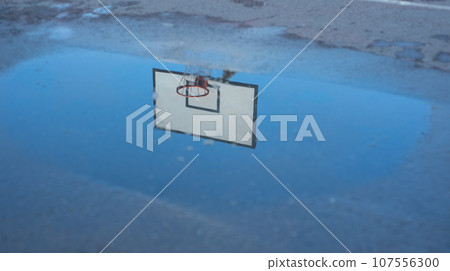 Reflection of a basketball ring in a puddle after the rain. Reflection of a basketball ring in a puddle after the rain. 107556300