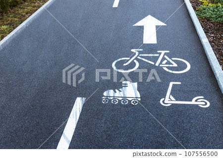 Bicycle road with painted white signs bicycle, roller skates, scooter and arrow direction of movement Bicycle road with painted white signs bicycle, roller skates, scooter and arrow direction of movement 107556500