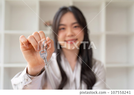 Portrait of happy young woman in modern flat house or apartment looking at camera holding bunch of keys. Female client of real estate csale or rental property concept 107558241