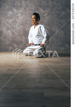A middle-aged male martial artist wearing a gi who sits straight. 107558559