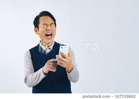 Middle-aged man laughing out loud while looking at his smartphone Middle-aged man laughing out loud while looking at his smartphone 107558602