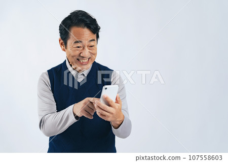 Middle-aged man smiling while looking at his smartphone Middle-aged man smiling while looking at his smartphone 107558603
