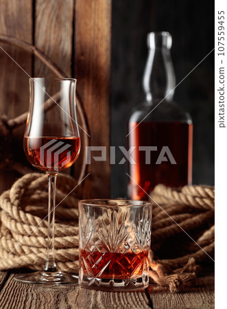 Crystal glass, snifter, and bottle with rum, cognac, or whiskey. Crystal glass, snifter, and bottle with rum, cognac, or whiskey. 107559455