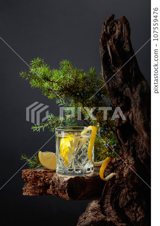 Cocktail gin-tonic with lemon in a crystal glass on an old board. 107559476