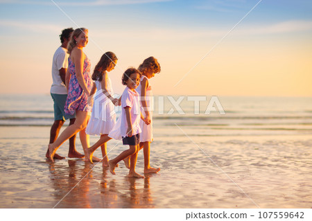 Family walking on tropical beach at sunset Family walking on tropical beach at sunset 107559642