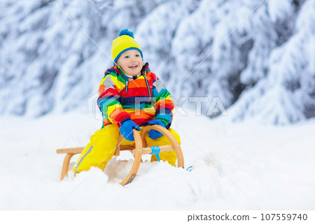 Boy on sled ride. Child sledding. Kid on sledge 107559740