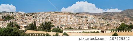 Beautiful panoramic view of the old Medina in Fes, Morocco (Fes El Bali Medina), a sea of buildings made of earthy tones. It's a bustling maze of life, with people and markets nestled in its heart Beautiful panoramic view of the old Medina in Fes, Morocco (Fes El Bali Medina), a sea of buildings made of earthy tones. It's a bustling maze of life, with people and markets nestled in its heart 107559842