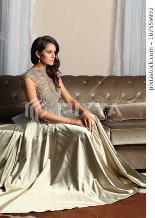 Brunette woman in luxurious dress sitting in a palace hall 107559932