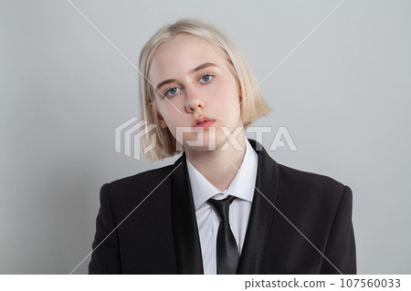 Blonde woman dressed in suit and tie poses on white background Blonde woman dressed in suit and tie poses on white background 107560033