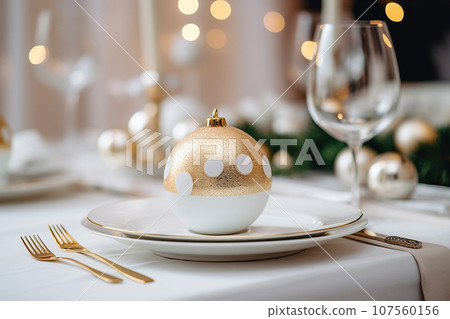 Beautiful table setting with Christmas decorations. Dishware, silverware and decorations on festive table, dinner table prepared for New Year's Eve. Christmas home decoration 107560156
