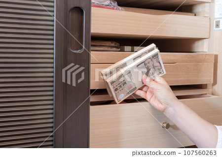 [A housewife hiding a wad of money in a Japanese dresser] 107560263