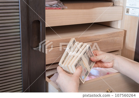 [A housewife hiding a wad of money in a Japanese dresser] 107560264