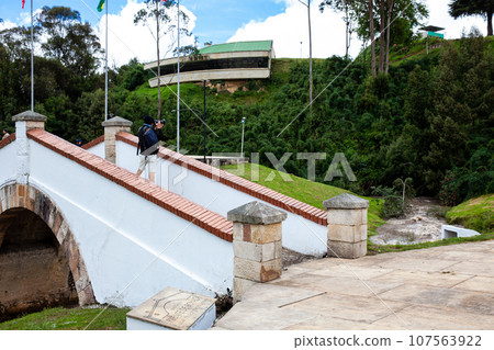Male tourist taking photos at the famous historic Bridge of Boyaca in Colombia. The Colombian independence Battle of Boyaca took place here on August 7, 1819. 107563922