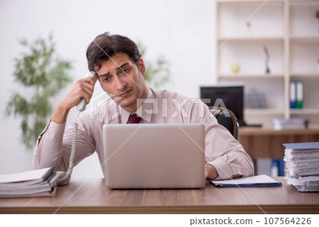 Young male employee and too much work in the office 107564226