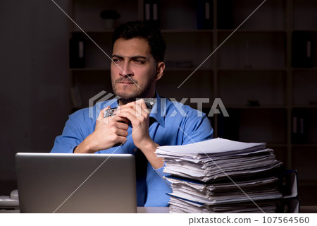 Young male employee working late in the office 107564560