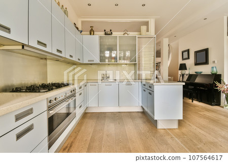 a kitchen with white cabinets and wood flooring in the middle of the room, there is a tv on the wall a kitchen with white cabinets and wood flooring in the middle of the room, there is a tv on the wall 107564617