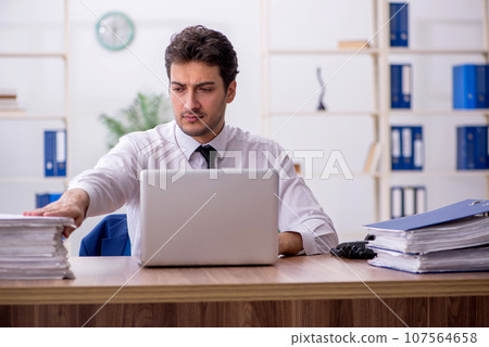 Young male employee and too much work in the office 107564658