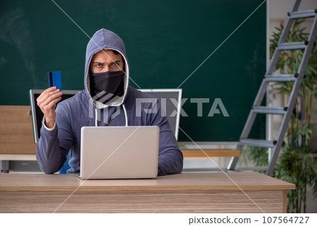 Young male hacker sitting in the classroom 107564727