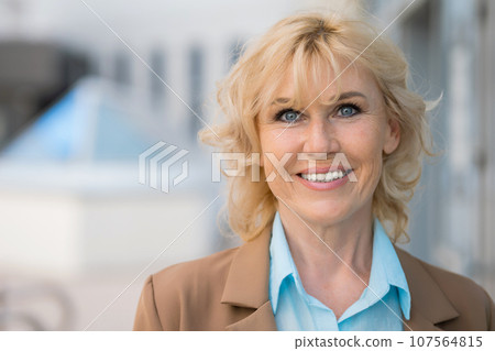 Mature businesswoman in formal suit smiles posing at camera Mature businesswoman in formal suit smiles posing at camera 107564815