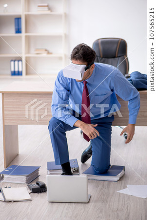 Young male employee enjoying virtual glasses at workplace 107565215