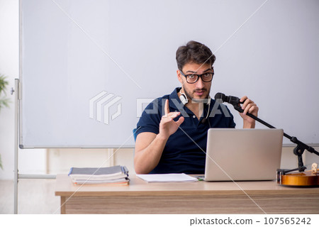 Young male music teacher sitting in the classroom 107565242