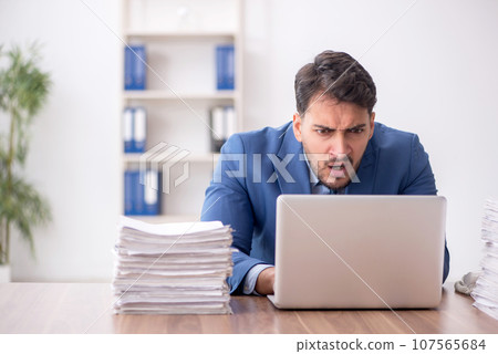 Young male employee and too much work in the office 107565684