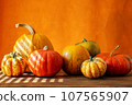 A row of orange pumpkins on a wooden surface with an orange background and a place to copy 107565907
