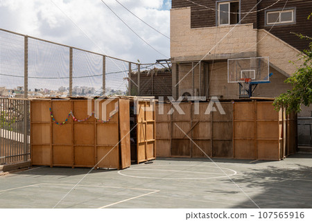 Wooden sukkahs in a yard of a residential building in town Hebron town on holiday Sukkot Wooden sukkahs in a yard of a residential building in town Hebron town on holiday Sukkot 107565916