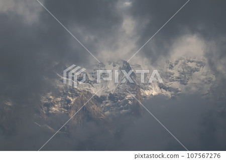 Landscape with snow-covered Himalayan mountains visible through gray clouds Landscape with snow-covered Himalayan mountains visible through gray clouds 107567276