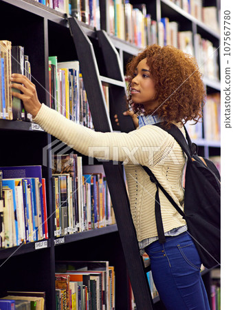 Black woman search for book in library, student at college and study for exam or research for project on campus. Education, learning and academic development with female person on ladder by bookshelf Black woman search for book in library, student at college and study for exam or research for project on campus. Education, learning and academic development with female person on ladder by bookshelf 107567780