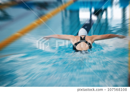 Sports, back or girl training in swimming pool for a race competition, exercise or cardio workout. Blurry swimmer, butterfly or healthy woman exercising with fitness speed or motivation in water Sports, back or girl training in swimming pool for a race competition, exercise or cardio workout. Blurry swimmer, butterfly or healthy woman exercising with fitness speed or motivation in water 107568108