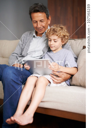 Tablet, child or grandpa streaming movie or film on online subscription in retirement at home to relax. Family, grandfather or kid loves watching fun videos with a senior or mature old man on sofa 107568289