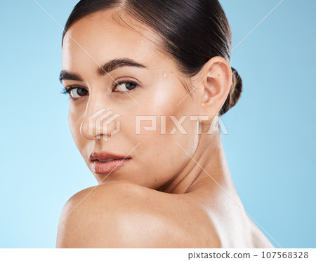 Portrait, beauty and shoulder with a model woman in studio on a blue background for natural skincare. Face, skin and cosmetics with an attractive young female posing to promote a luxury product Portrait, beauty and shoulder with a model woman in studio on a blue background for natural skincare. Face, skin and cosmetics with an attractive young female posing to promote a luxury product 107568328