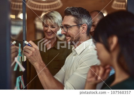 Businessman, meeting and planning in teamwork for brainstorming, collaboration or strategy at office. Man employee in leadership, presentation or training staff in team project or sticky note plan 107568357