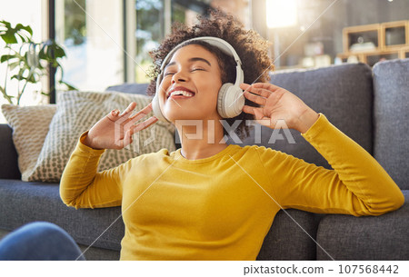 Headphones, music and happy woman with mental health, wellness dance or youth audio streaming service at home. Relax, floor and dancing of young african person with audio electronics or technology 107568442
