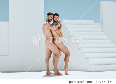 Art, romantic embrace and naked men pose together in sun, blue sky and Greek architecture in lgbt photography. Creative pride aesthetic, artistic passion and love, nude gay couple with athletic body. 107569130