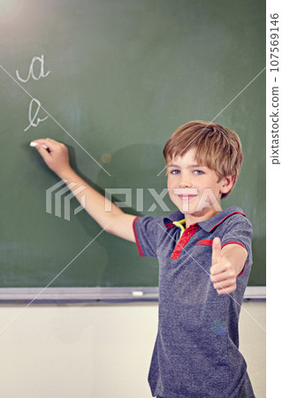 Portrait, child writing and thumbs up on blackboard in classroom, elementary school and mockup. Chalkboard, education student and kid with hand gesture for like emoji, agreement and learning to write 107569146