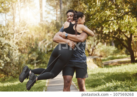 Fitness, spinning and couple hug in park outdoors for exercise, training and running for cardio workout. Dating, happy and interracial man and woman embrace for wellness, healthy body and sports 107569268